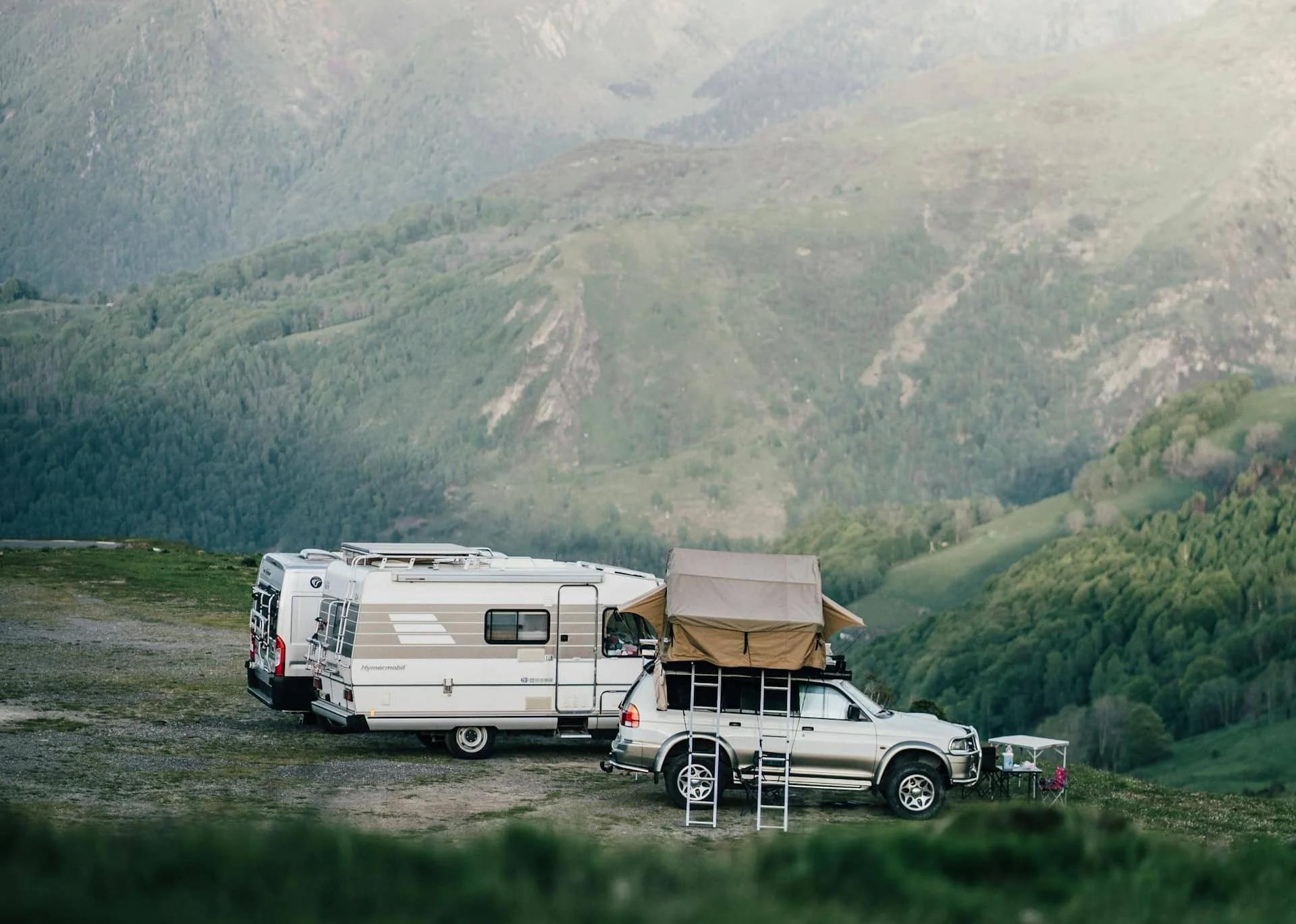 Camper vans and a rooftop-tent vehicle camped in a mountain valley